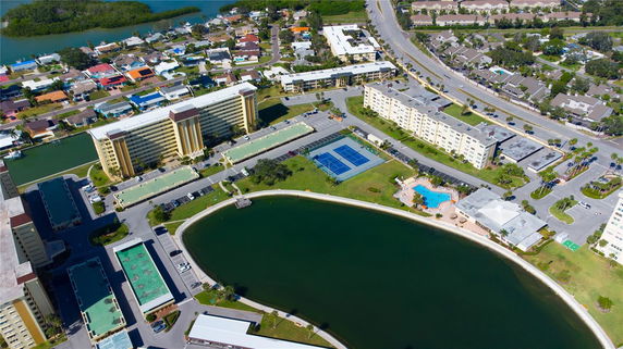 Aerial view of residential buildings with surrounding waterways, tennis courts, and a swimming pool.