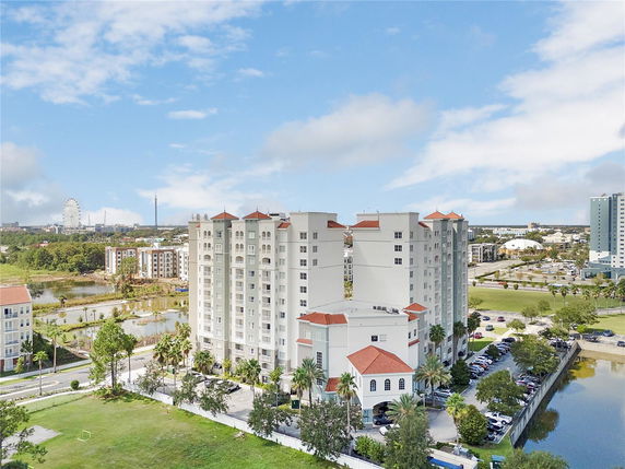Front view of a multi-story apartment building with surrounding parking area and nearby water body.