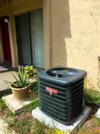 Outdoor view of a building with sliding glass door and air conditioning unit.
