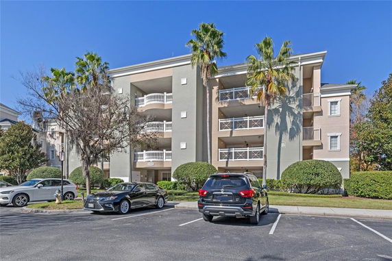 Front view of a multi-story apartment building with balconies and parking area.