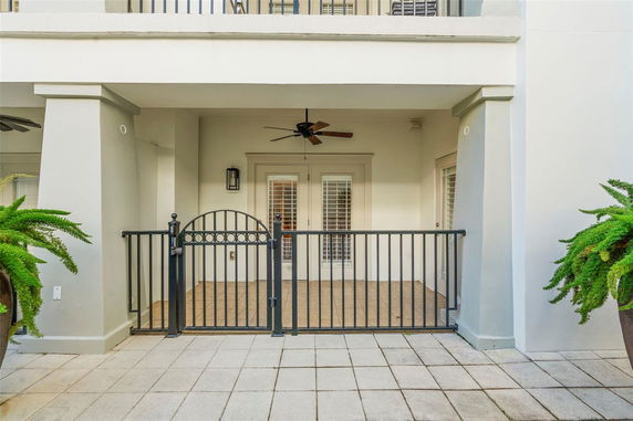 Front view of a building with a gated patio and ceiling fan.