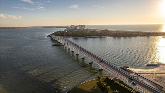 Panoramic view of a long bridge over water with buildings and coastline in the distance.