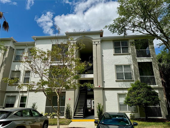 Front view of a multi-story residential building with balconies and staircase access.
