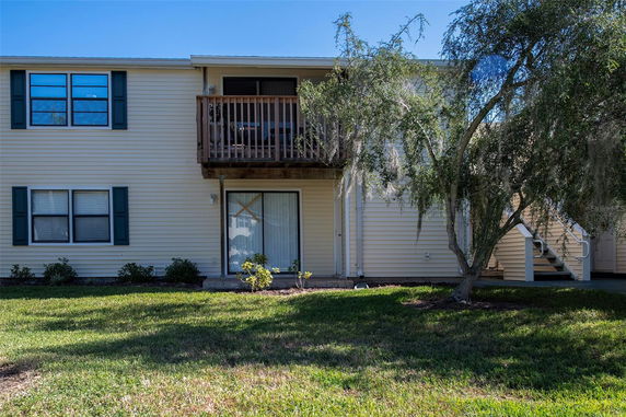 Front view of a two-story house with a small balcony and sliding glass door.