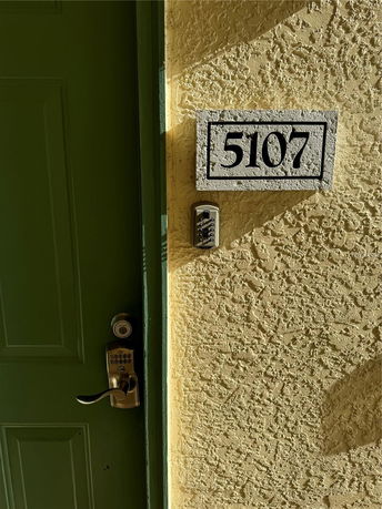 Close-up view of building entrance with a green door and unit number 5107.