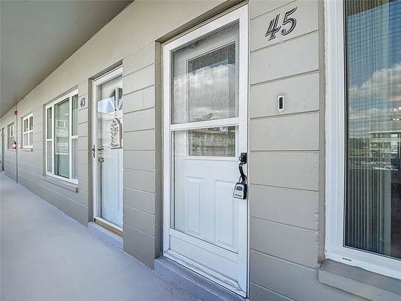 Exterior view of an apartment door with adjacent windows on a corridor.