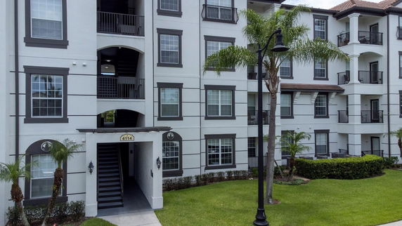 Front view of a multi-story apartment building with balconies and a stairwell entrance.