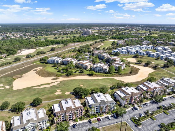Aerial view showcasing a wide expanse of residential buildings surrounded by golf courses and greenery.