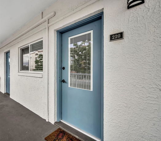 Front view of a building entrance with a blue door and a window.