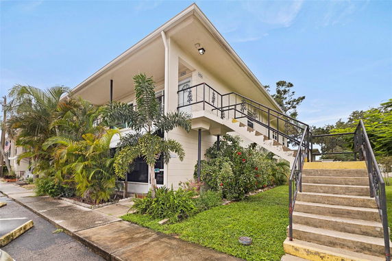 Front view of a two-story building with exterior stairs and a balcony.