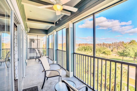 Panoramic view from a screened balcony with chairs and table overlooking trees and the sky.