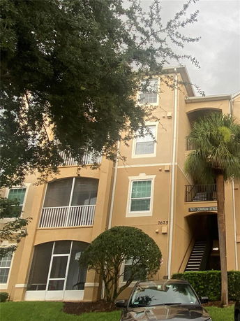Front view of a multi-story apartment building with balconies and trees nearby.
