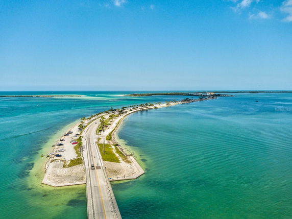 Panoramic view of a coastal road with surrounding turquoise waters and a distant shoreline.