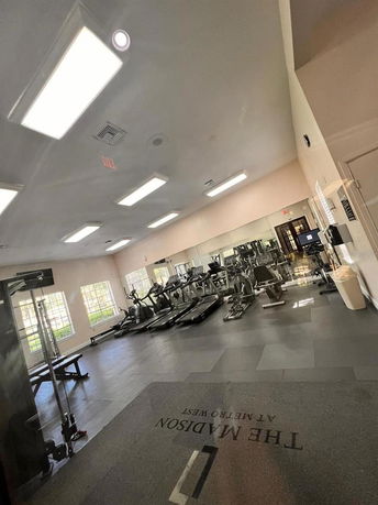 Interior view of a gym with exercise equipment and large windows.