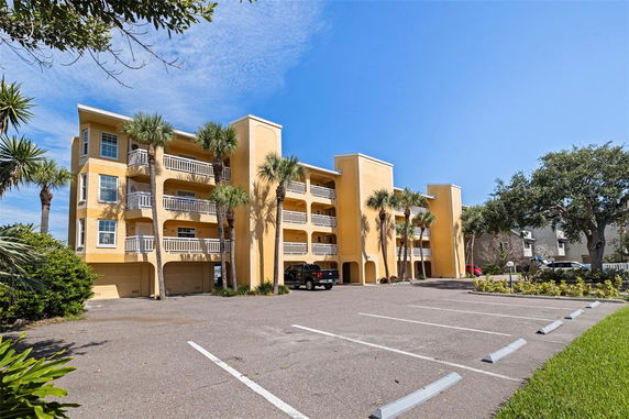 Front view of a multi-story building with balconies and garage spaces.