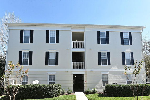 Front view of a three-story apartment building with multiple windows and a central staircase.