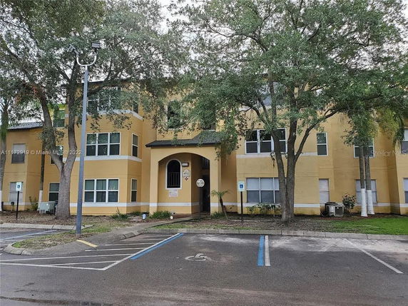Front view of a multi-story yellow building with several windows and an arched entrance.