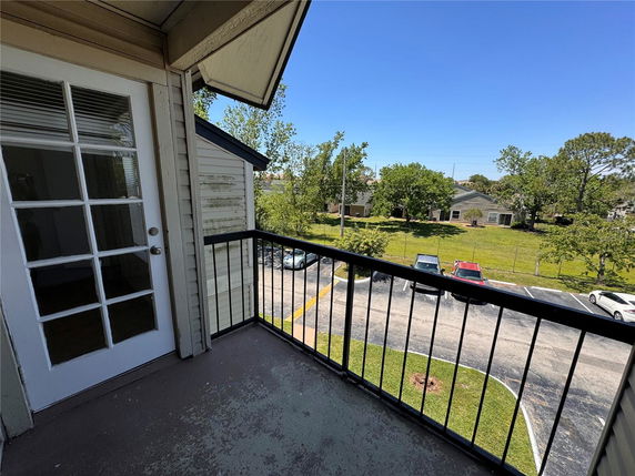 View from a balcony looking out over a parking area and residential neighborhood.