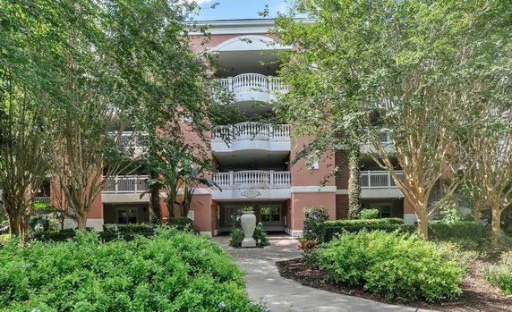 Front view of a multi-story building with balconies and a landscaped entrance.