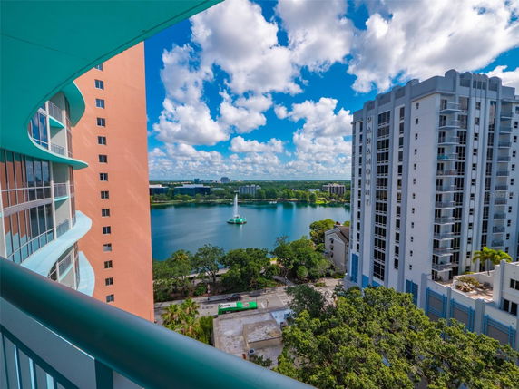 Panoramic view from a high-rise building overlooking another building and a lake.