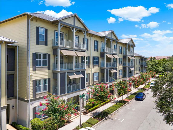 Front view of a multi-story apartment building with balconies and a street view.