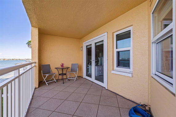 Balcony area with chairs and table offering a panoramic view of the water.