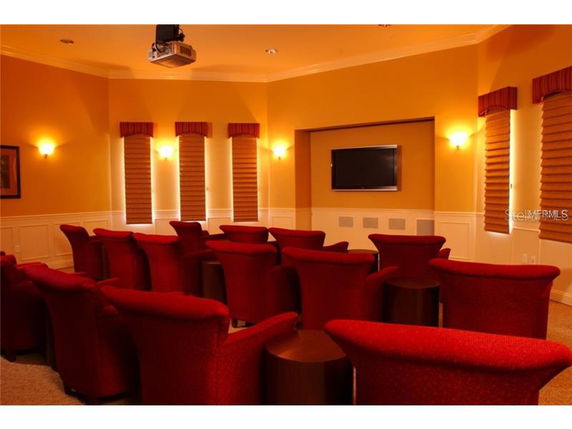 Home theater room with red seats and a wall-mounted screen.