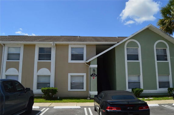 Front view of a two-story residential building with arched windows and a sloped roof.