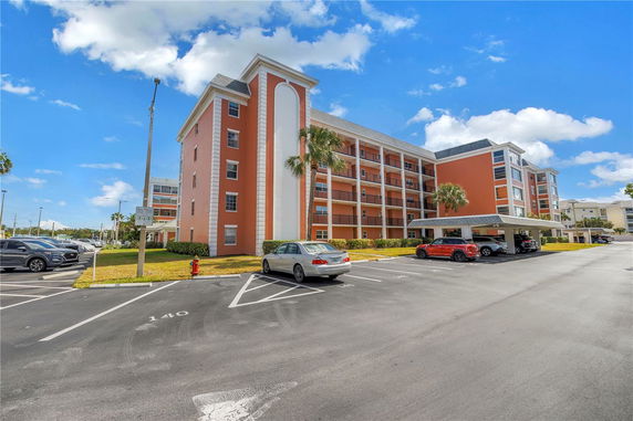 Front view of a multi-story apartment building with covered parking area.
