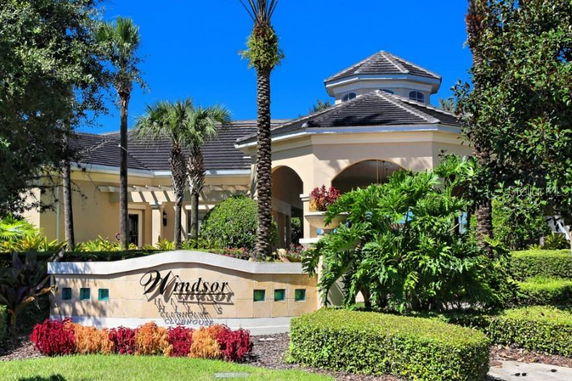 Front view of a clubhouse with a decorative sign and surrounding greenery.