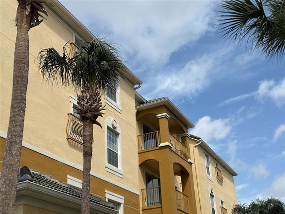 Front view of a multi-story building with balconies and a yellow and tan exterior.