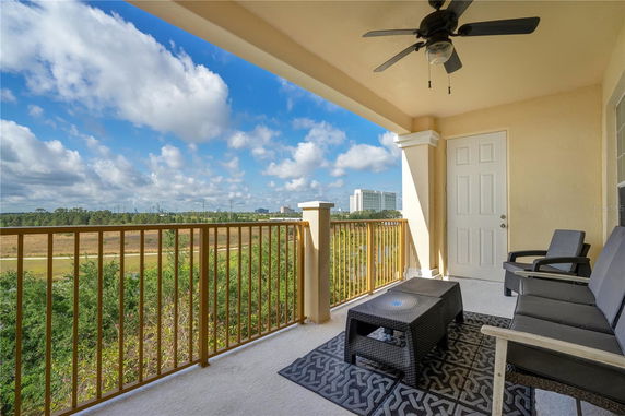 View from a balcony with railing overlooking greenery and a distant building.