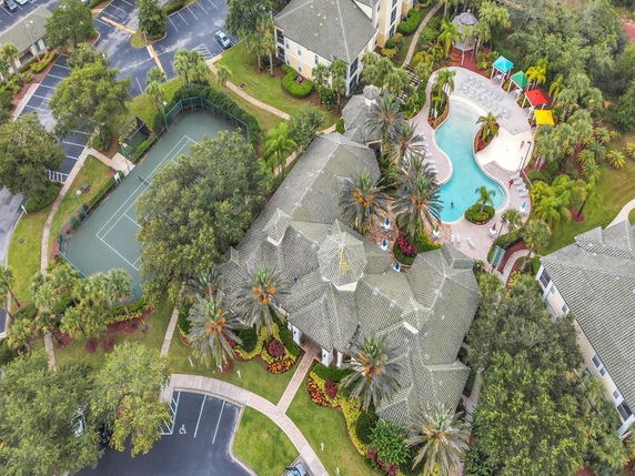 Aerial view of a residential complex with buildings, a swimming pool, and a tennis court.