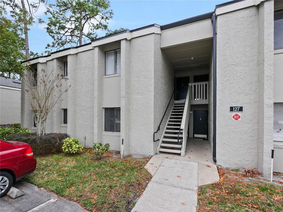 Front view of a two-story building with stairs leading to an upper entrance.