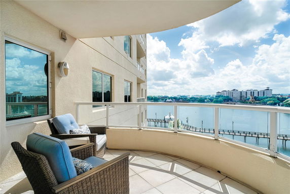 Balcony with chairs overlooking a waterfront and distant buildings.