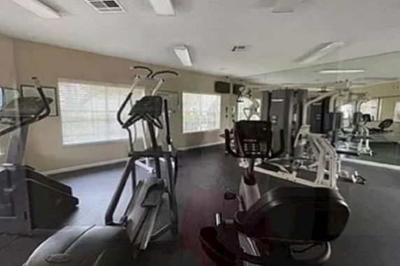 Interior view of a gym with exercise equipment and large windows.