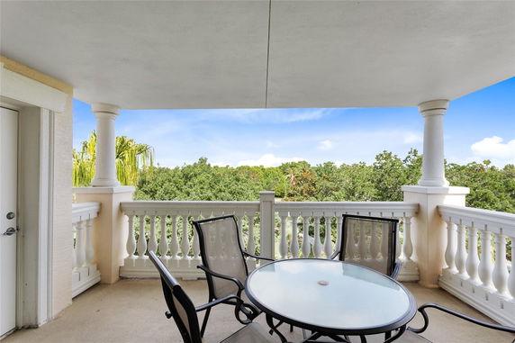 Balcony with outdoor seating overlooking lush greenery.