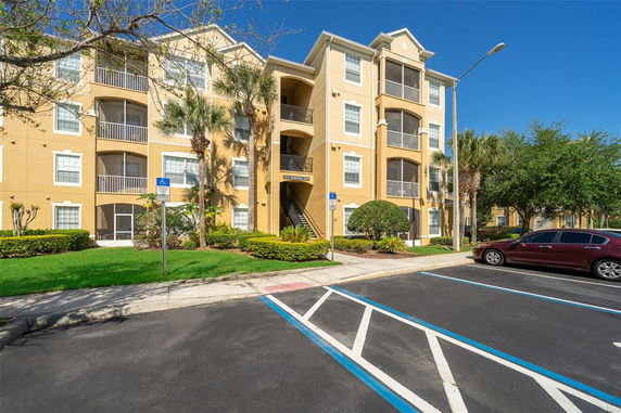 Front view of a multi-story residential building with balconies and covered parking.