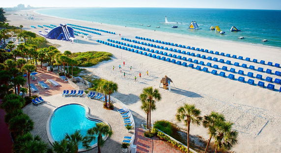 Panoramic view of a beachside resort with a swimming pool and beachfront cabanas.
