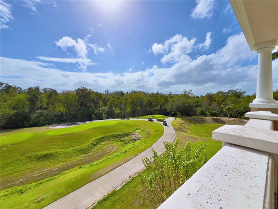 Panoramic view from a building balcony overlooking greenery and a golf course.