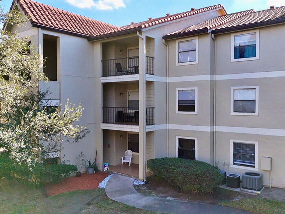 Front view of a multi-story apartment building with balconies and a tiled roof.