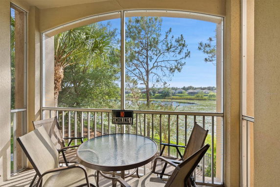 View from a screened balcony showing outdoor scenery with trees and a lake.