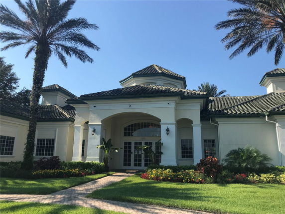 Front view of a large house with a grand entrance and tiled roof.