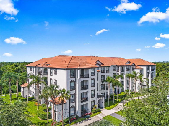 Front view of a multi-story apartment building with white facade and red tiled roof.