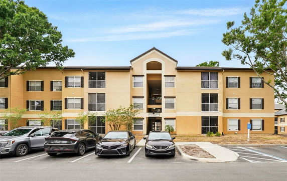 Front view of a three-story apartment building with parking area.