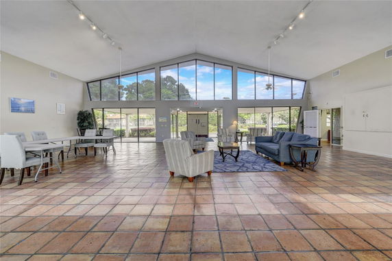 Spacious room with large windows, multiple seating areas, and tiled floor.