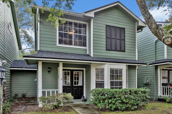 Front view of a two-story house with green siding and black accents.