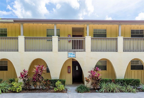 Front view of a two-story building with arches and a balcony.