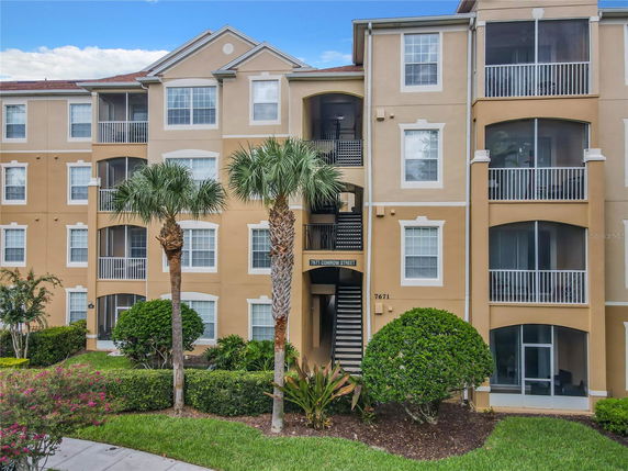 Front view of a multi-story apartment building with balconies and a staircase.