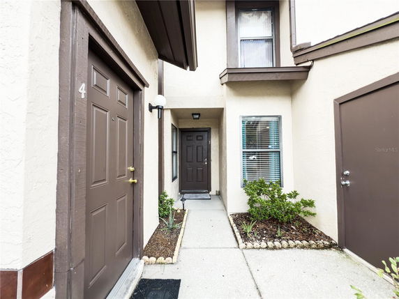 Front view of a townhouse entrance with brown doors and beige exterior.
